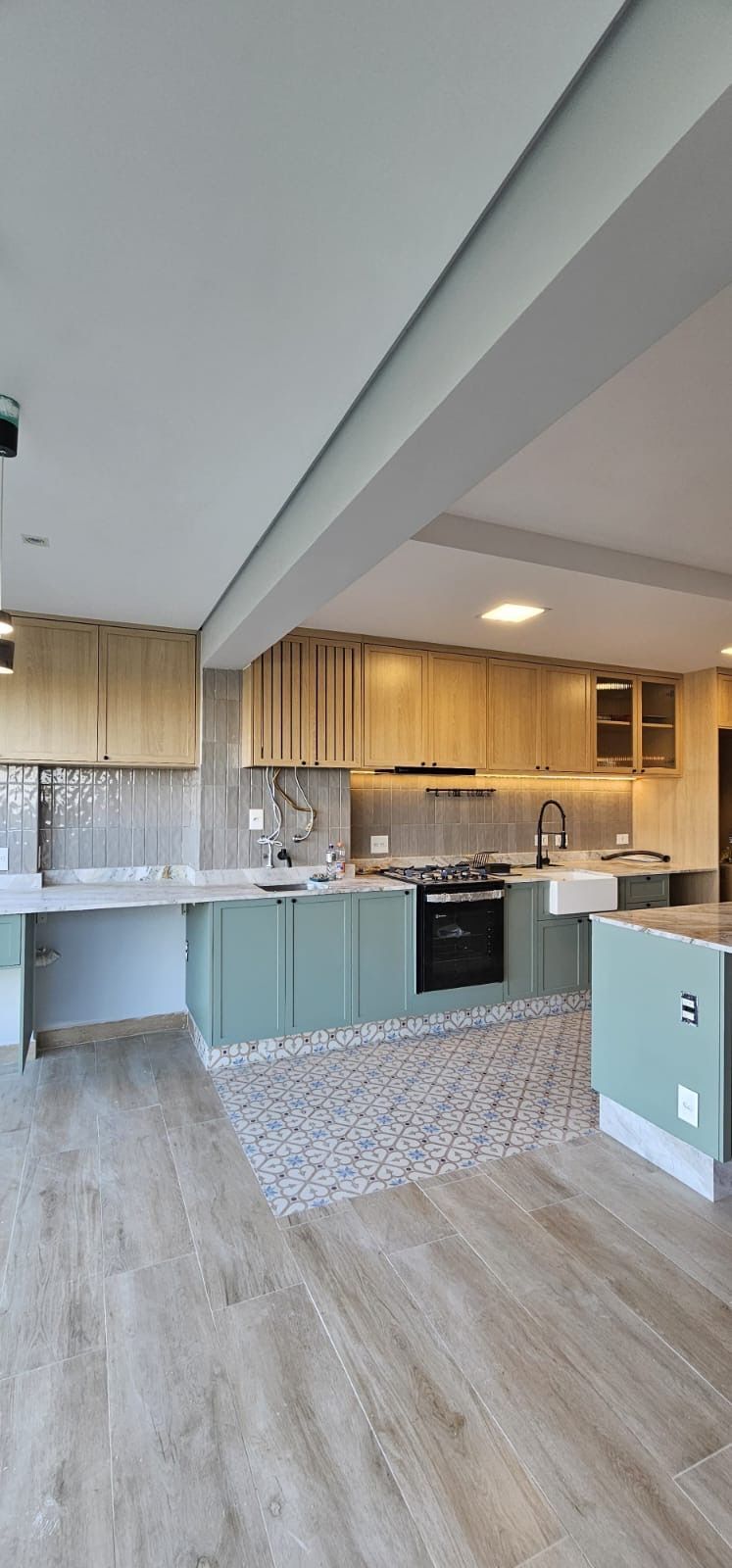 Cozinha moderna de conceito aberto com armários de madeira clara, backsplash de azulejos brancos e piso de madeira.