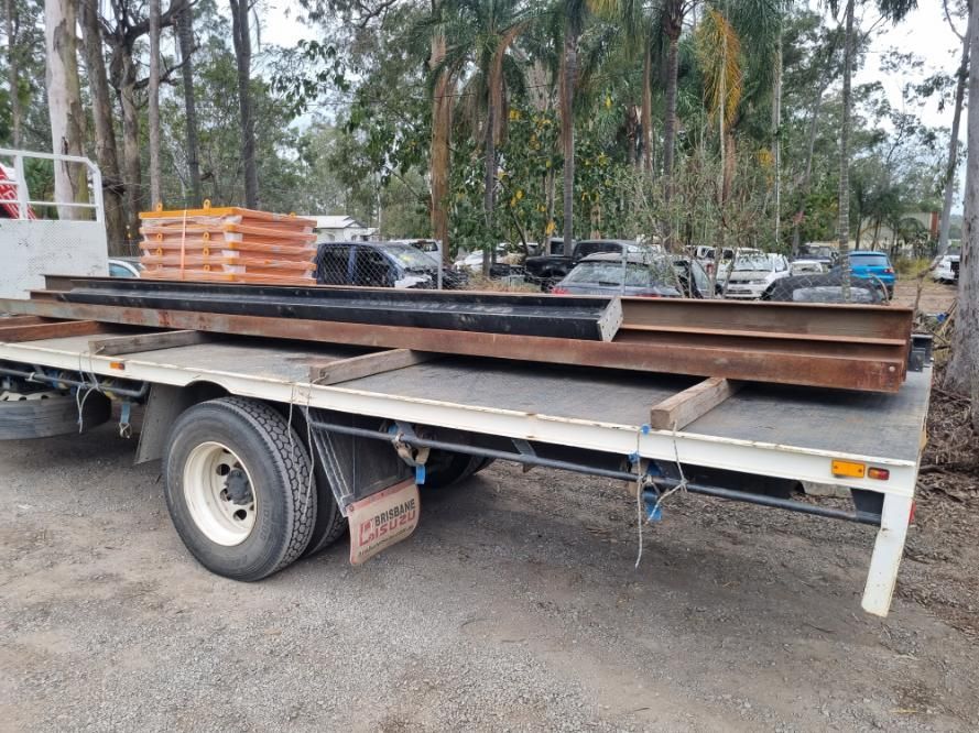 A Flatbed Truck is Carrying a Stack of Metal Beams — BS Crane Truck and Trailer Hire In Tewantin, QLD