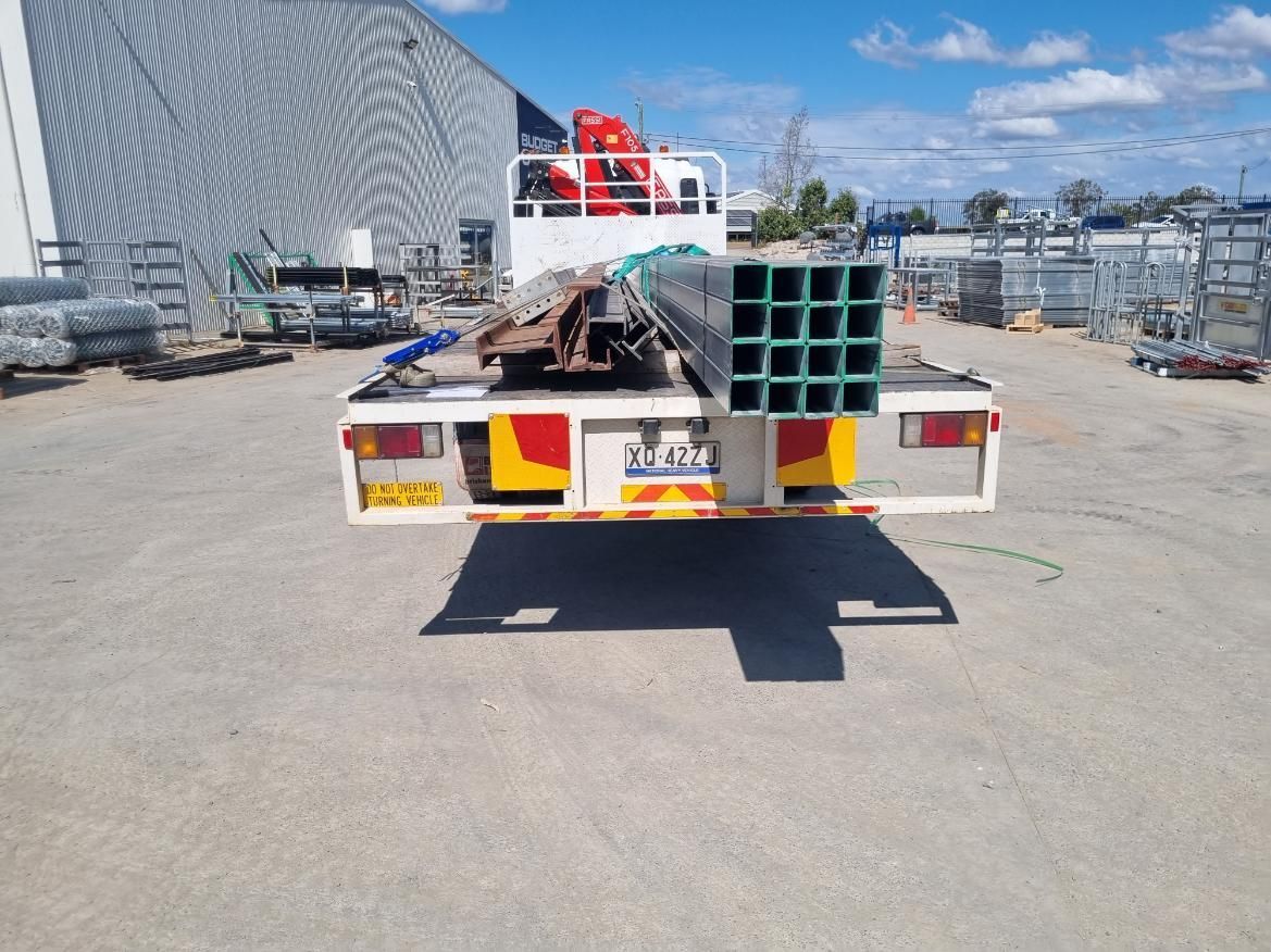 A Truck is Carrying a Bunch of Pipes on the Back of It — BS Crane Truck and Trailer Hire In Tewantin, QLD