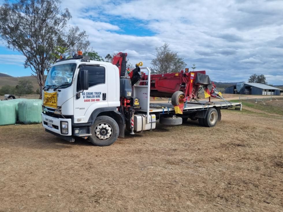 A Tow Truck With a Crane Attached to It is Parked in a Dirt Field — BS Crane Truck and Trailer Hire In Yandina, QLD