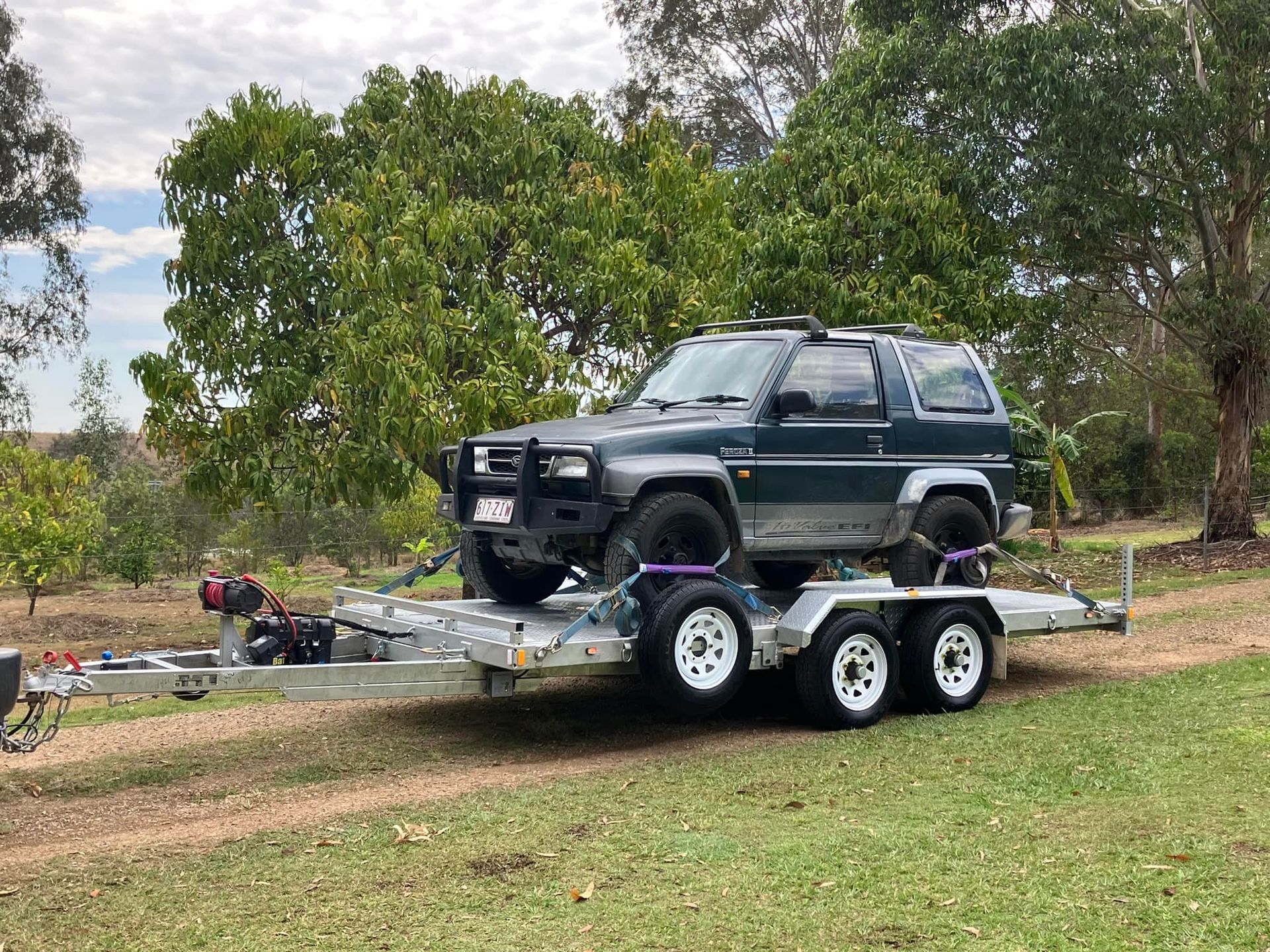 Small pickup car being carried by yellow car trailer — Crane Truck or Car Trailer in Long Flat, QLD