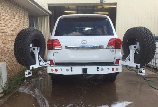 A White Suv With Two Spare Tires Attached To It Is Parked In Front Of A Brick Building — Emerald 4x4 in Emerald, QLD