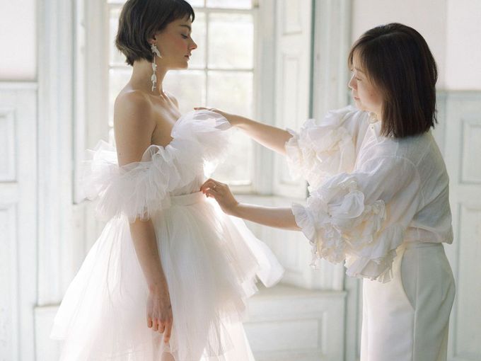 A woman is helping a woman in a wedding dress.