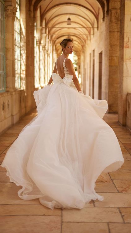 A woman in a white wedding dress is standing in a hallway.