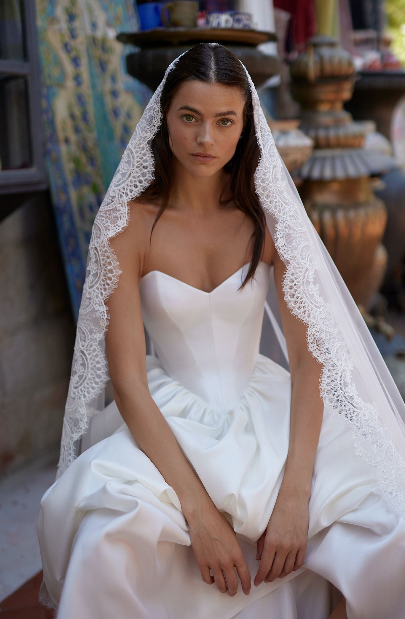 A bride in a designer wedding gown with a lacey veil