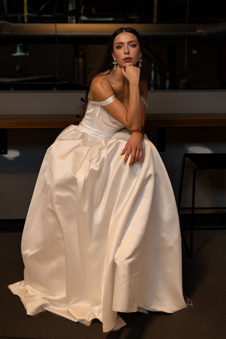 A woman is wearing a white dress with long sleeves and a plunging neckline.