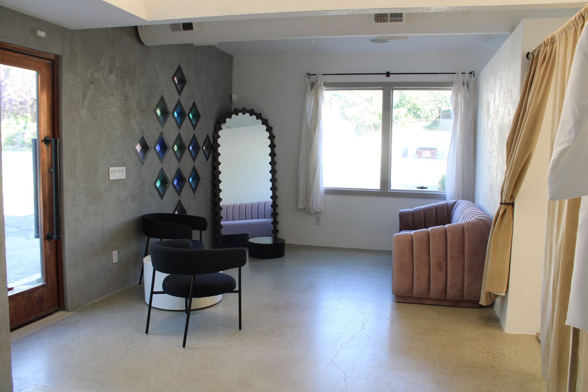 A private bridal suite at Renee Atelier including a full length mirror, two modern seats, and a velvet couch