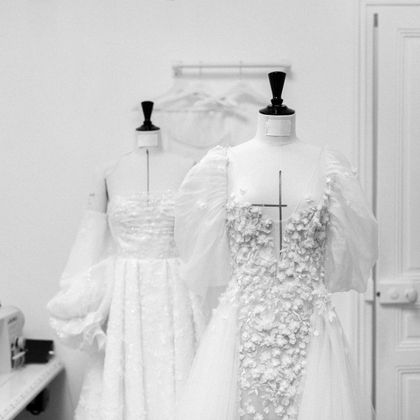 A black and white photo of two wedding dresses on mannequins.