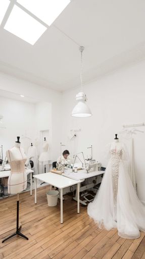 A man is working on a wedding dress in a studio.