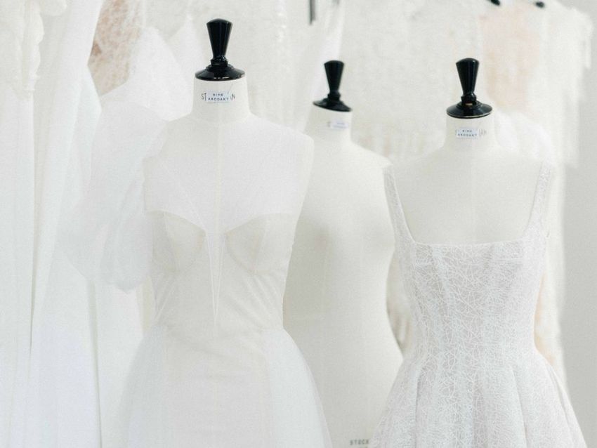 A row of white mannequins with white dresses on them.