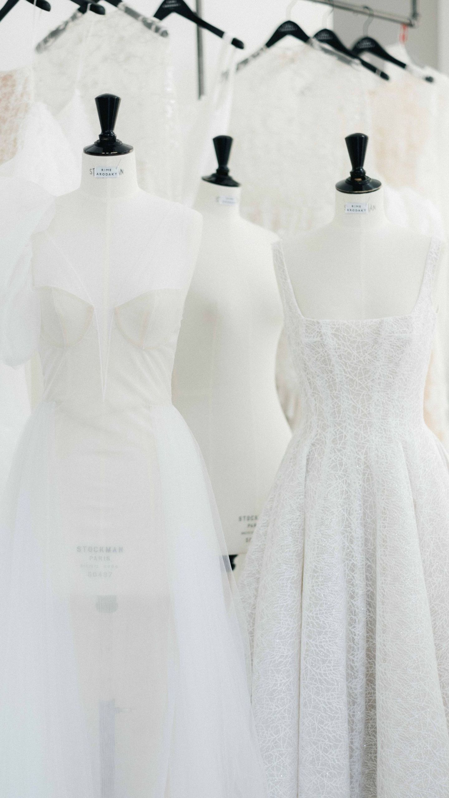 A row of white wedding dresses on mannequins in a store