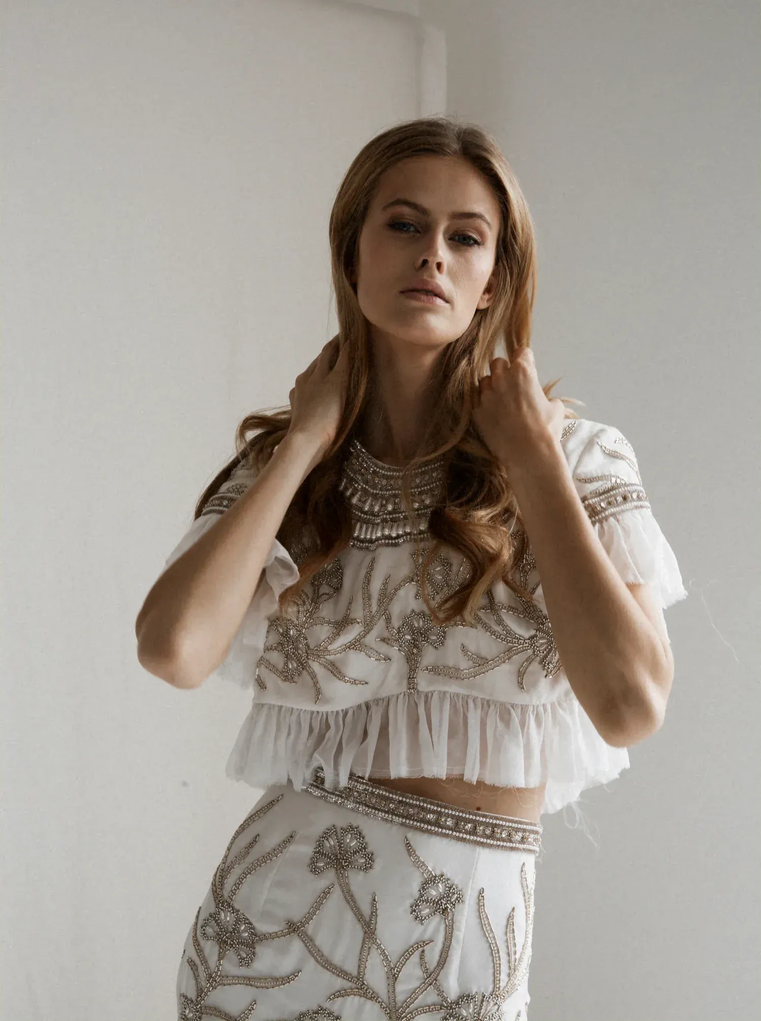 A bride posing in a gorgeous wedding gown with intricate gold beading details