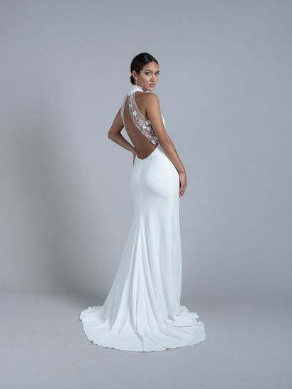 A woman in a bridal gown from Renee Atelier posing in front of a large boulder
