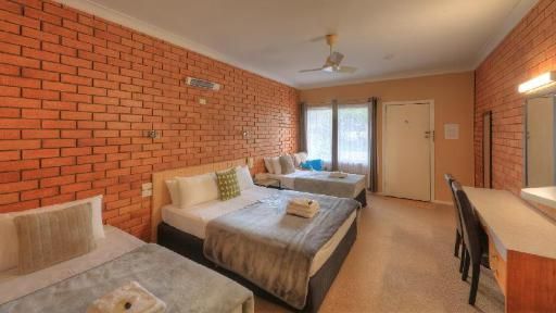 Hotel Room With Three Beds And A Brick Wall — Hilldrop Motor Inn In Waterview Heights, NSW