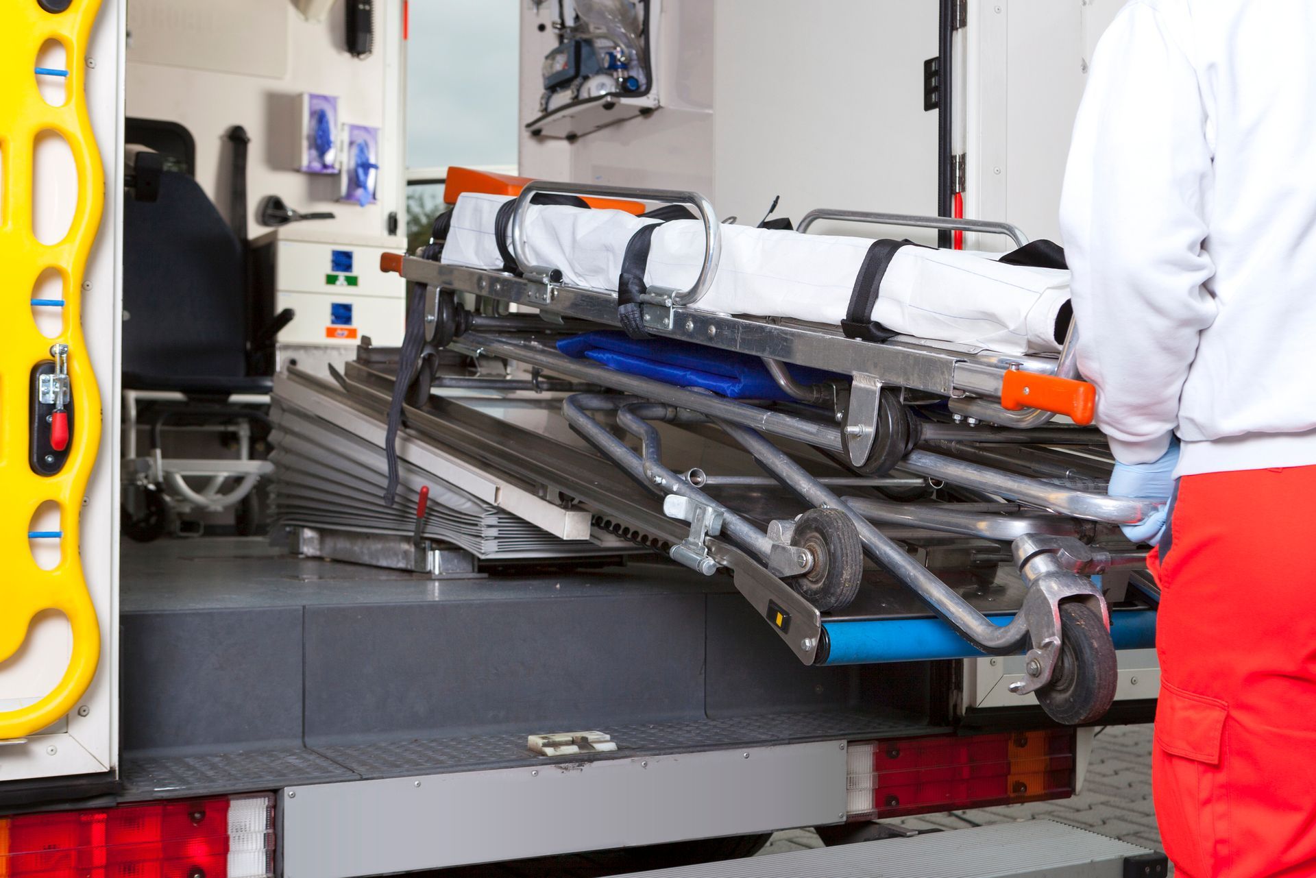 A man is loading an ambulance with a stretcher in the back.