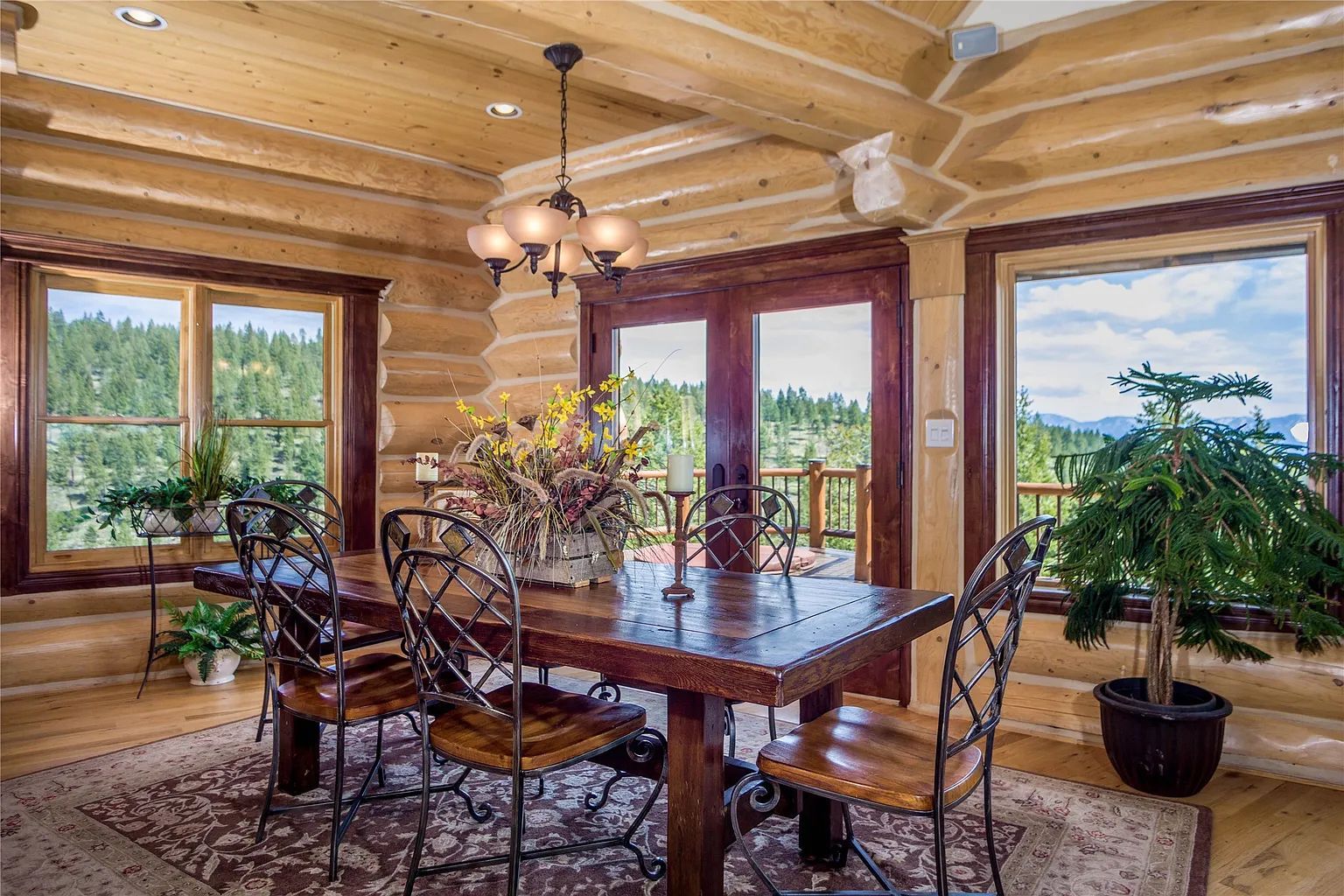 Dining area with large windows and scenic forest views, offering a cozy atmosphere for vacation rental guests at The Ridge.