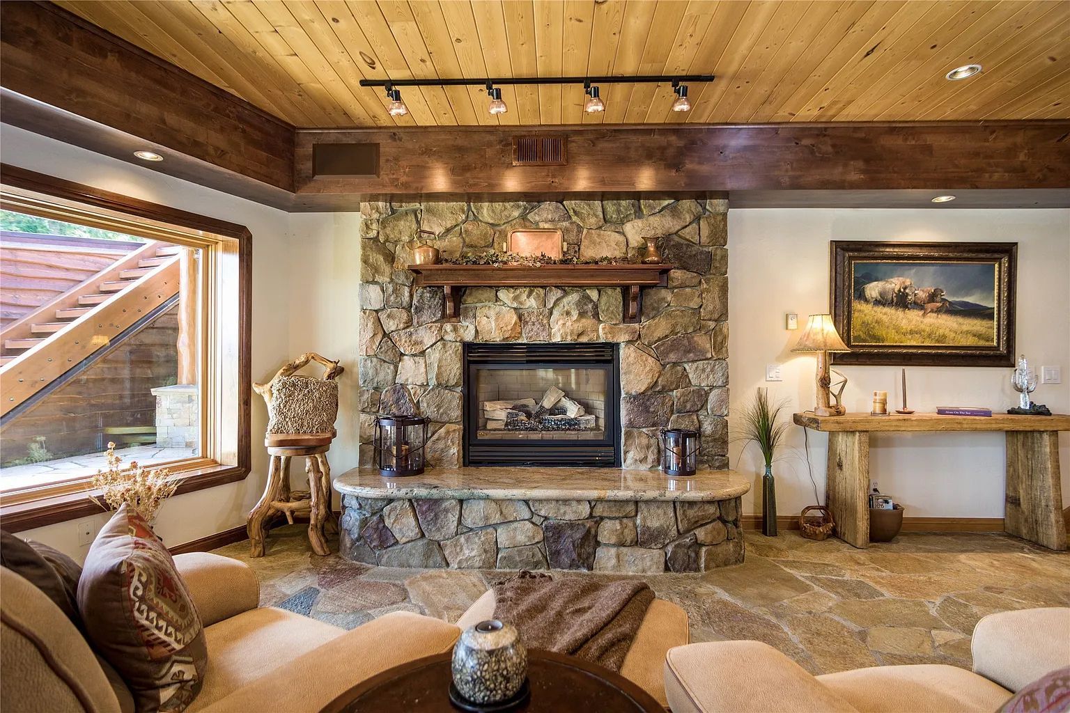 Downstairs lounge with stone fireplace, inviting space for guests at The Ridge lodge vacation rental.