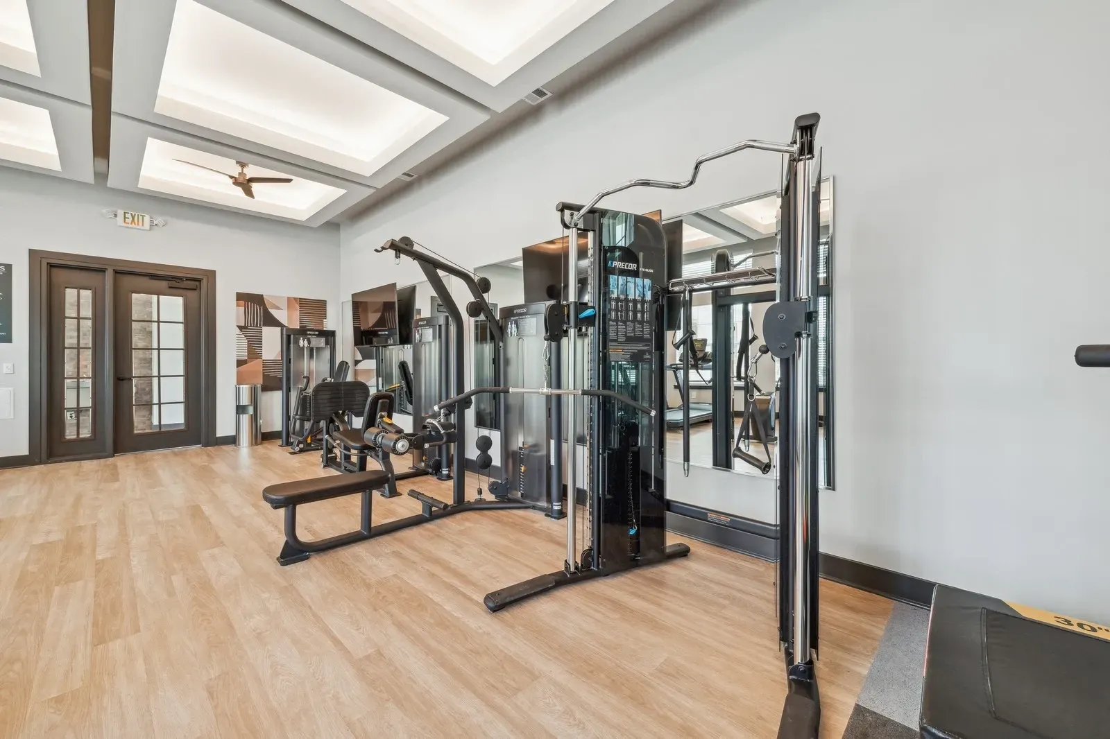 Interior of an apartment community gym with weight machines and benches.