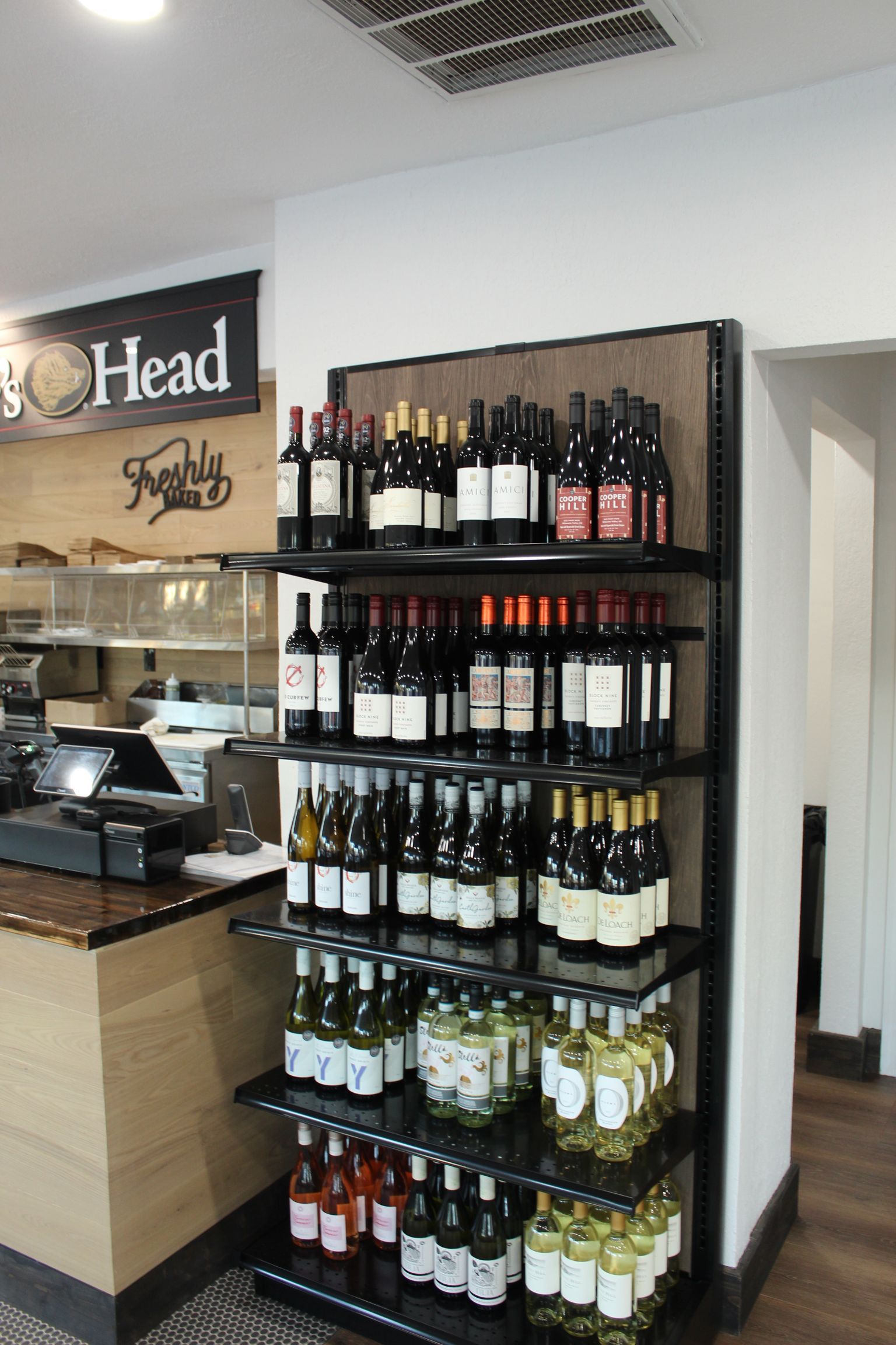 A display of wine bottles in a store with a sign that says head