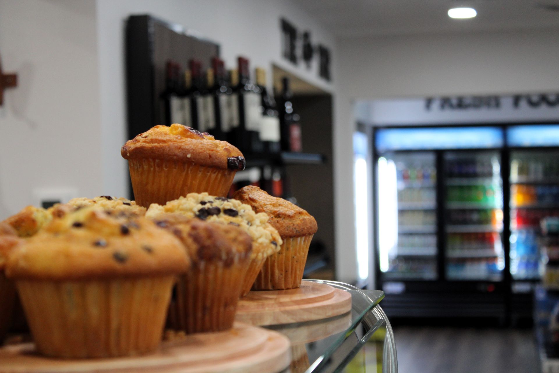 A bunch of muffins are sitting on a shelf in a store.