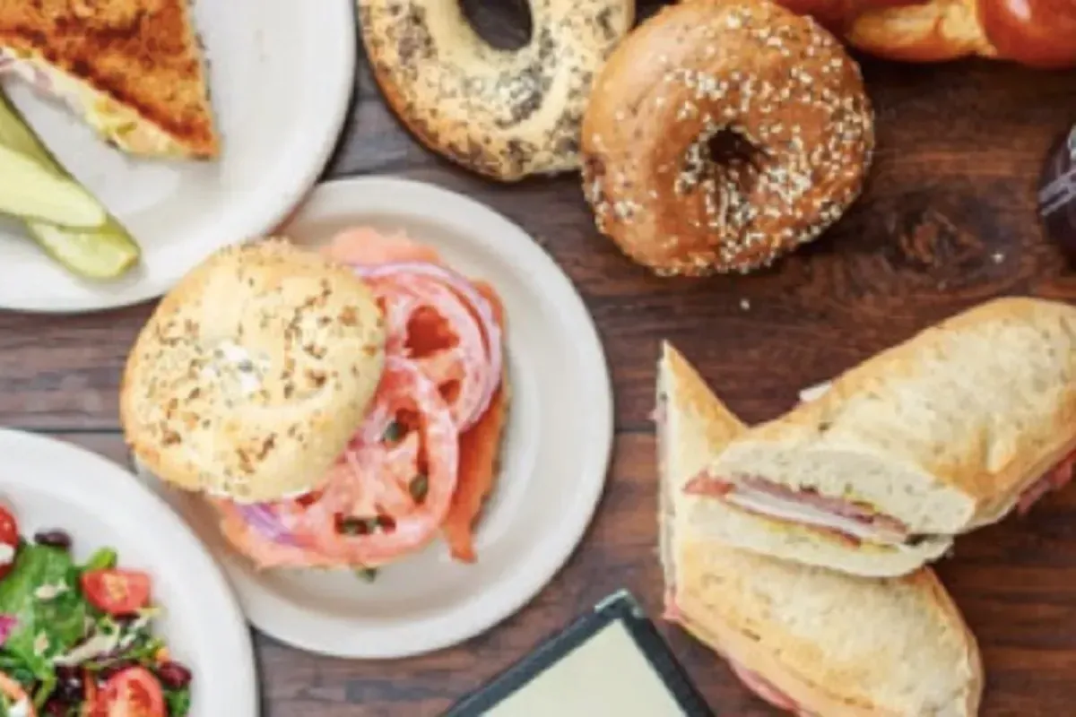 A table topped with plates of food including sandwiches and bagels
