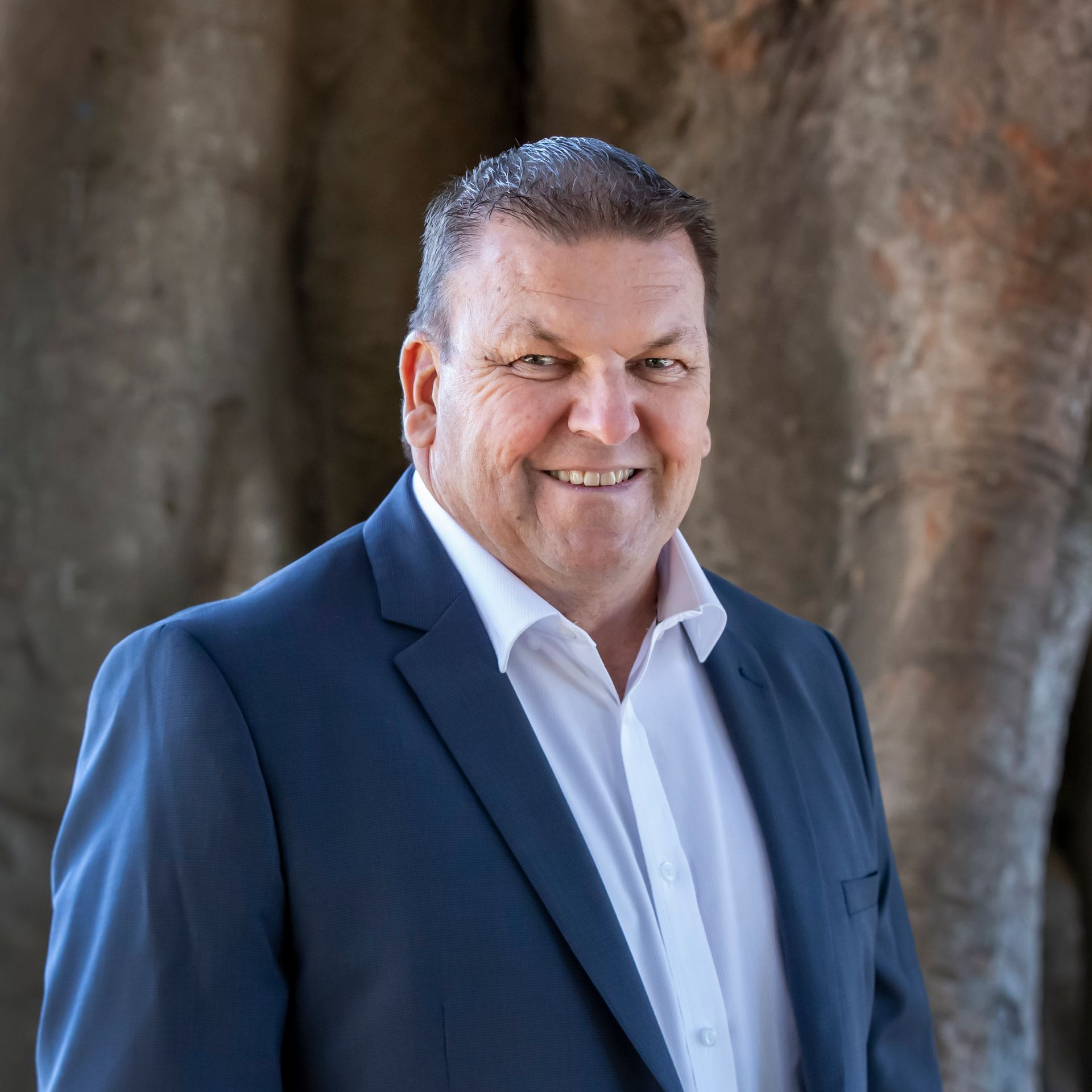 Man in suit smiles against a textured background.