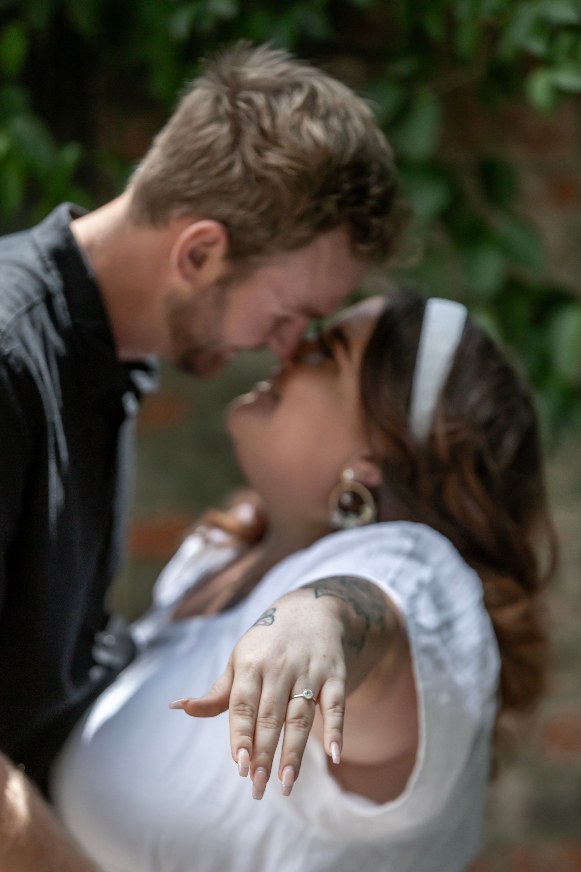 Woman shows off engagement ring, embraces man.