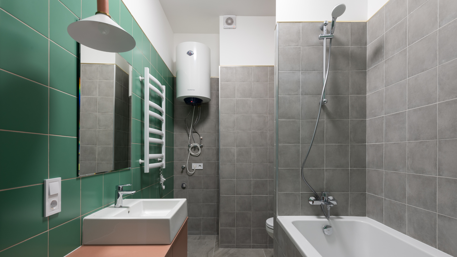 Bathroom with green and gray tile, white fixtures, and a wall-mounted water heater.
