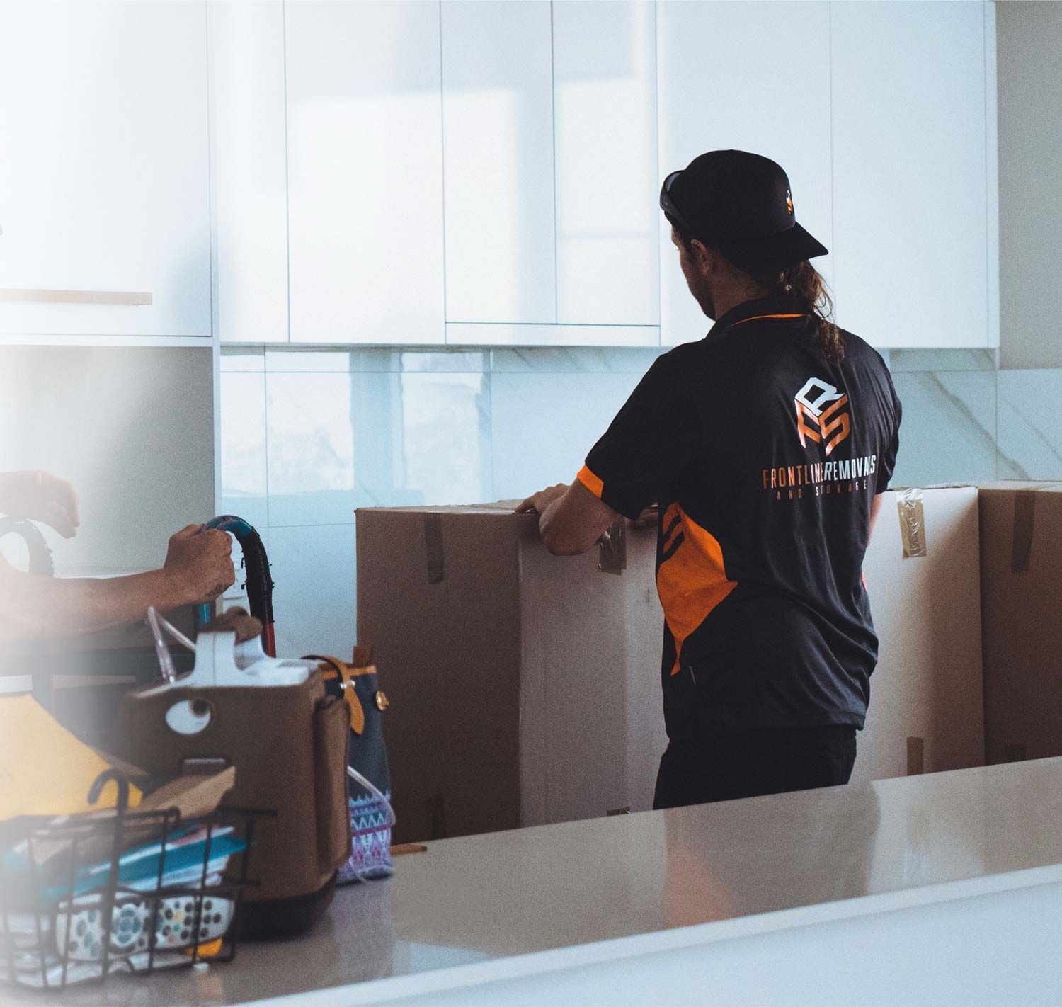 A Man Dressed In A Frontline Removals Uniform Is Packing A Moving Box — Frontline Removals And Storage in Gold Coast, QLD