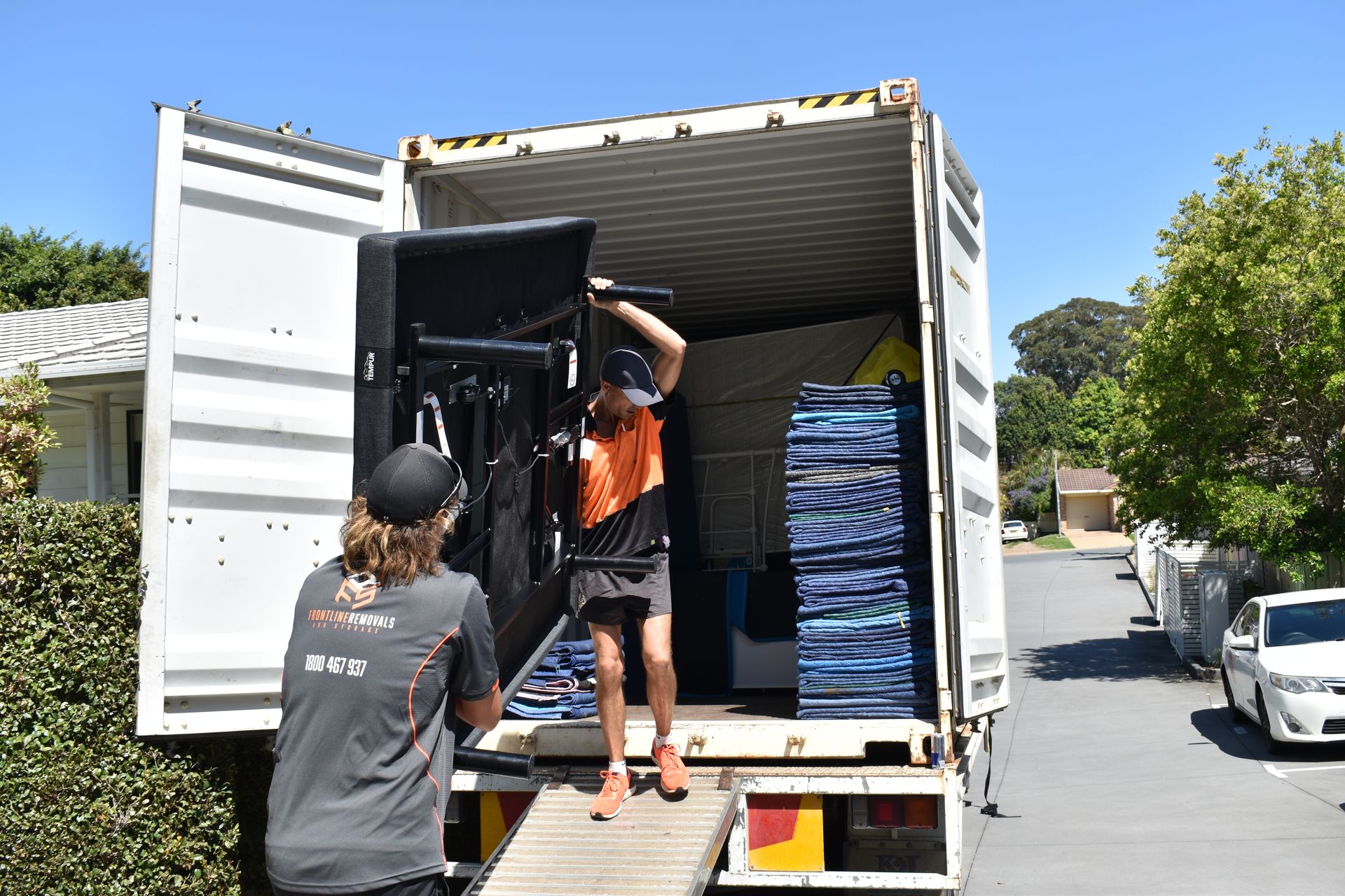 A Man And A Woman Sit On A Couch Surrounded By Cardboard Boxes— Frontline Removals And Storage in Grafton, NSW