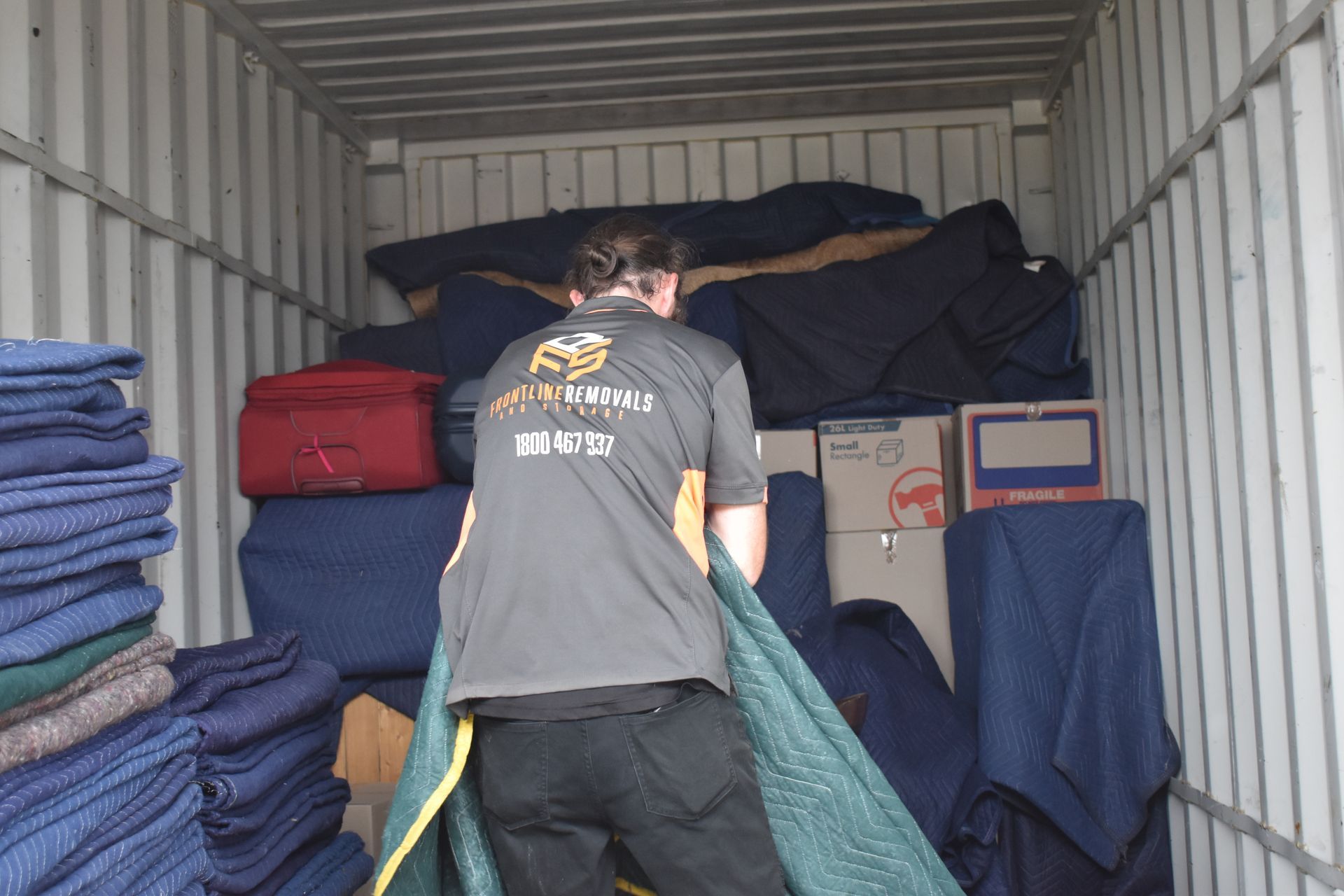 A Man Is Taping A Cardboard Box With A Yellow Tape Dispenser — Frontline Removals And Storage in Kempsey, NSW