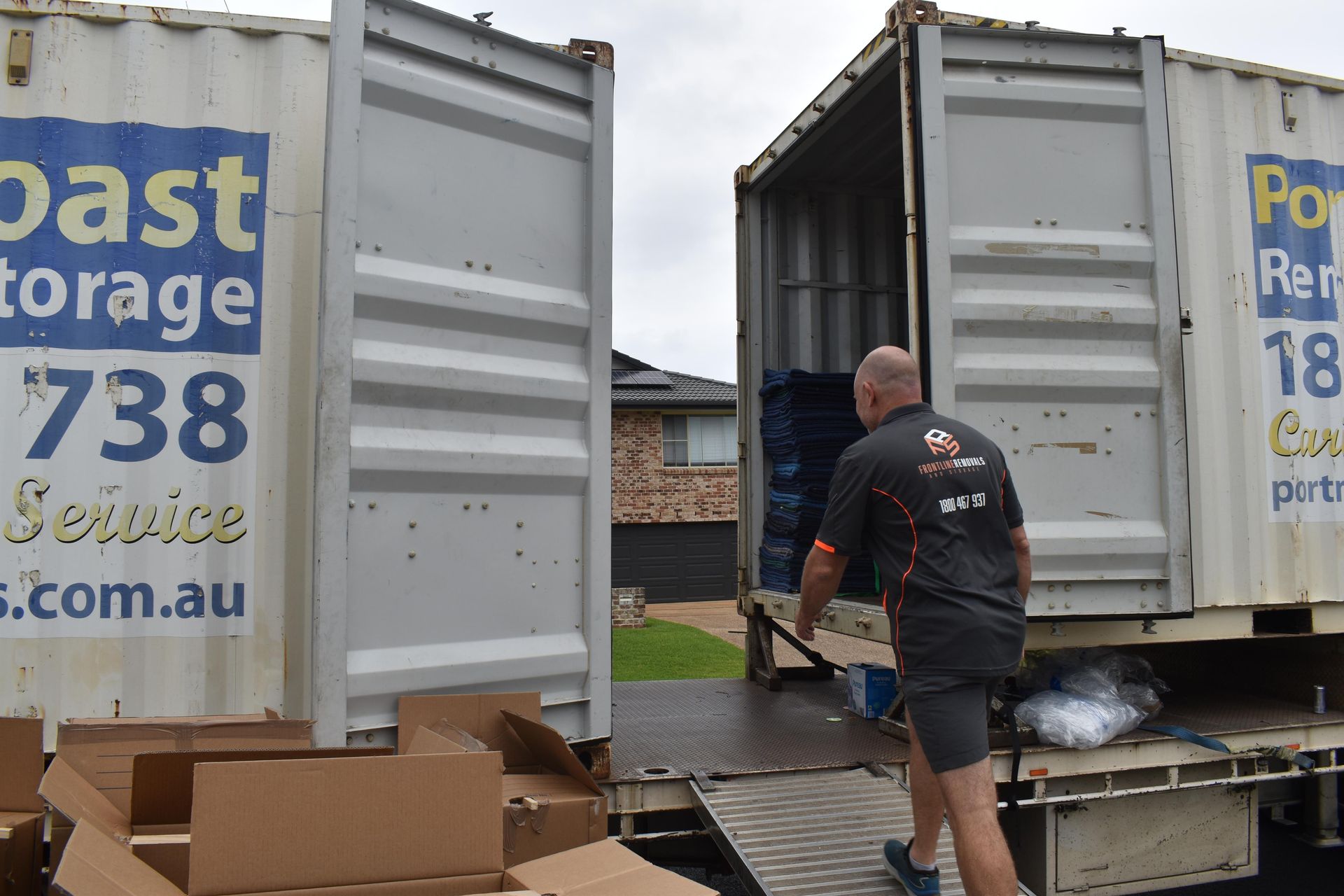 A Man Loading Boxes Into a Shipping Container on a Truck — Frontline Removals And Storage in Port Macquarie, NSW