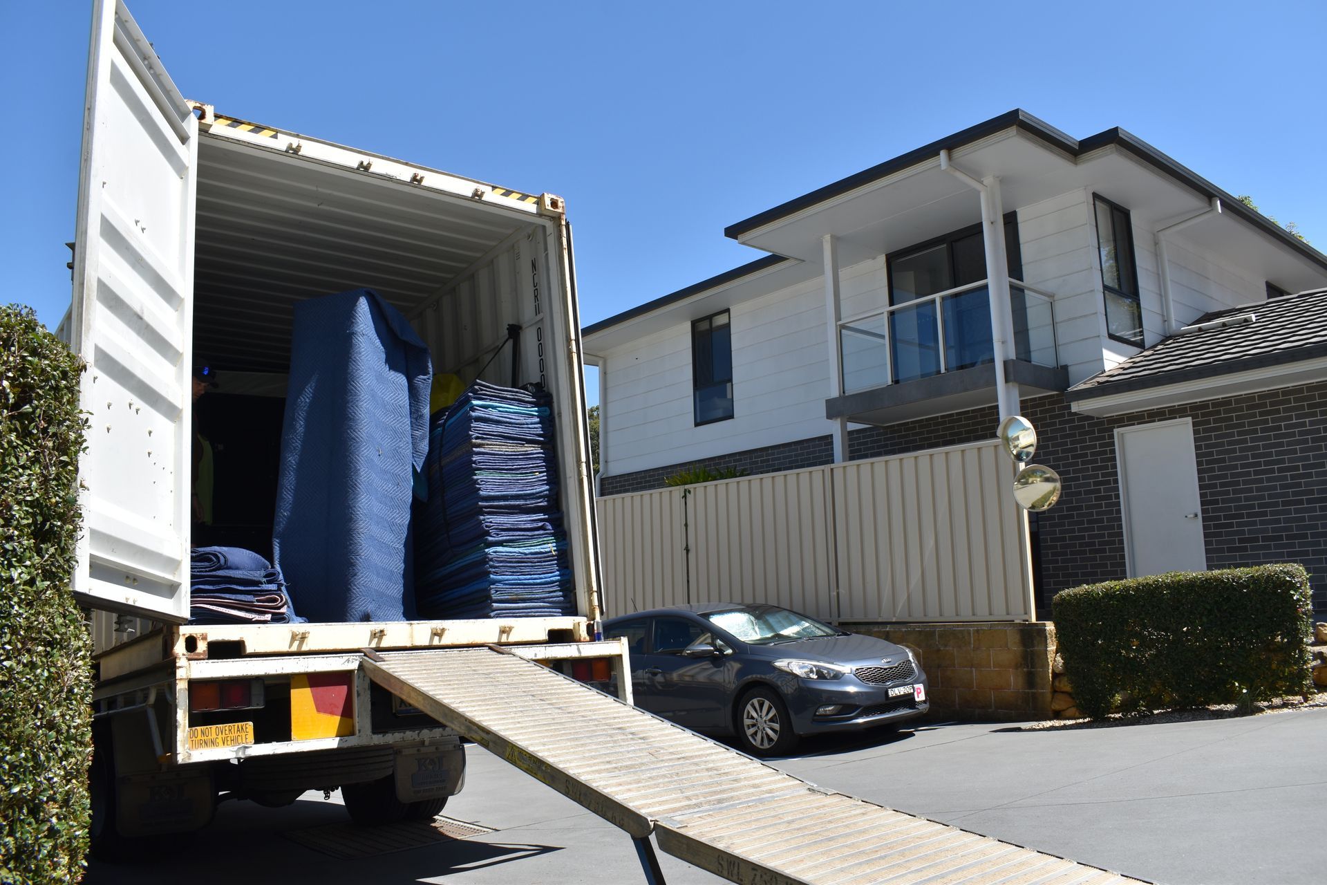 A Man And A Woman Are Sitting On A Large Moving Box In A Room — Frontline Removals And Storage in Brisbane, QLD