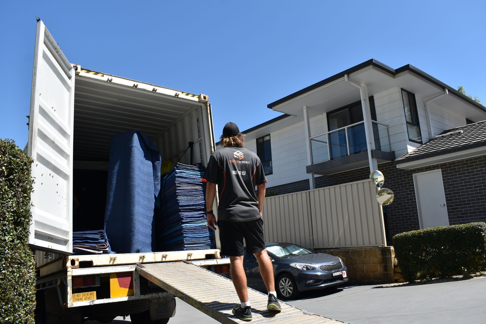 A Man And A Woman Are Covering A Couch With Plastic Wrap — Frontline Removals And Storage in Coffs Harbour, NSW
