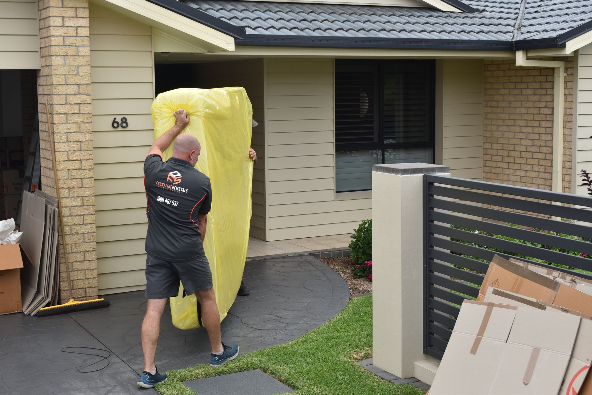 A Woman Is Carrying A Cardboard Box In A Bedroom — Frontline Removals And Storage in Sydney, NSW