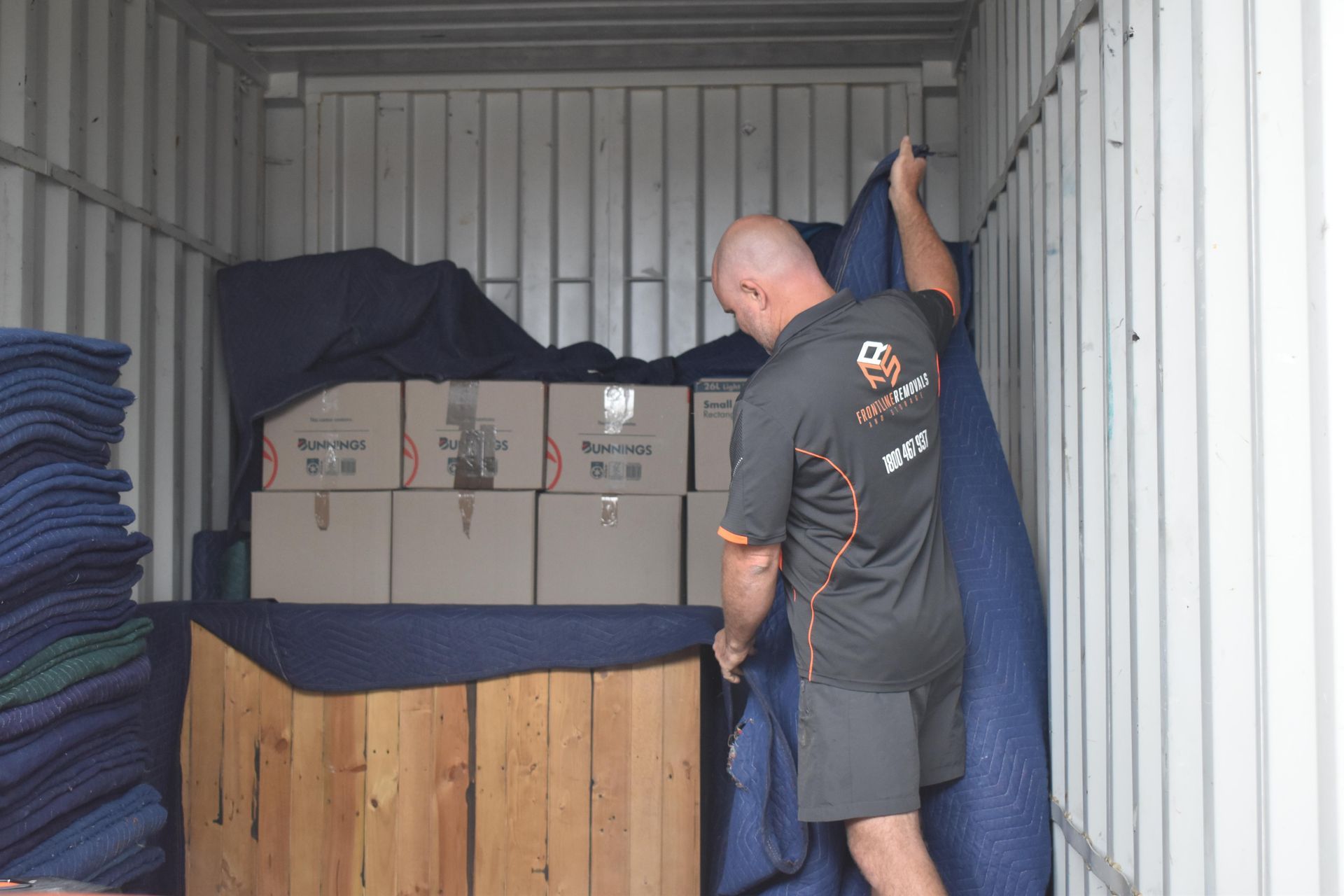 Man loading boxes into a storage container, placing padding — Frontline Removals And Storage in Port