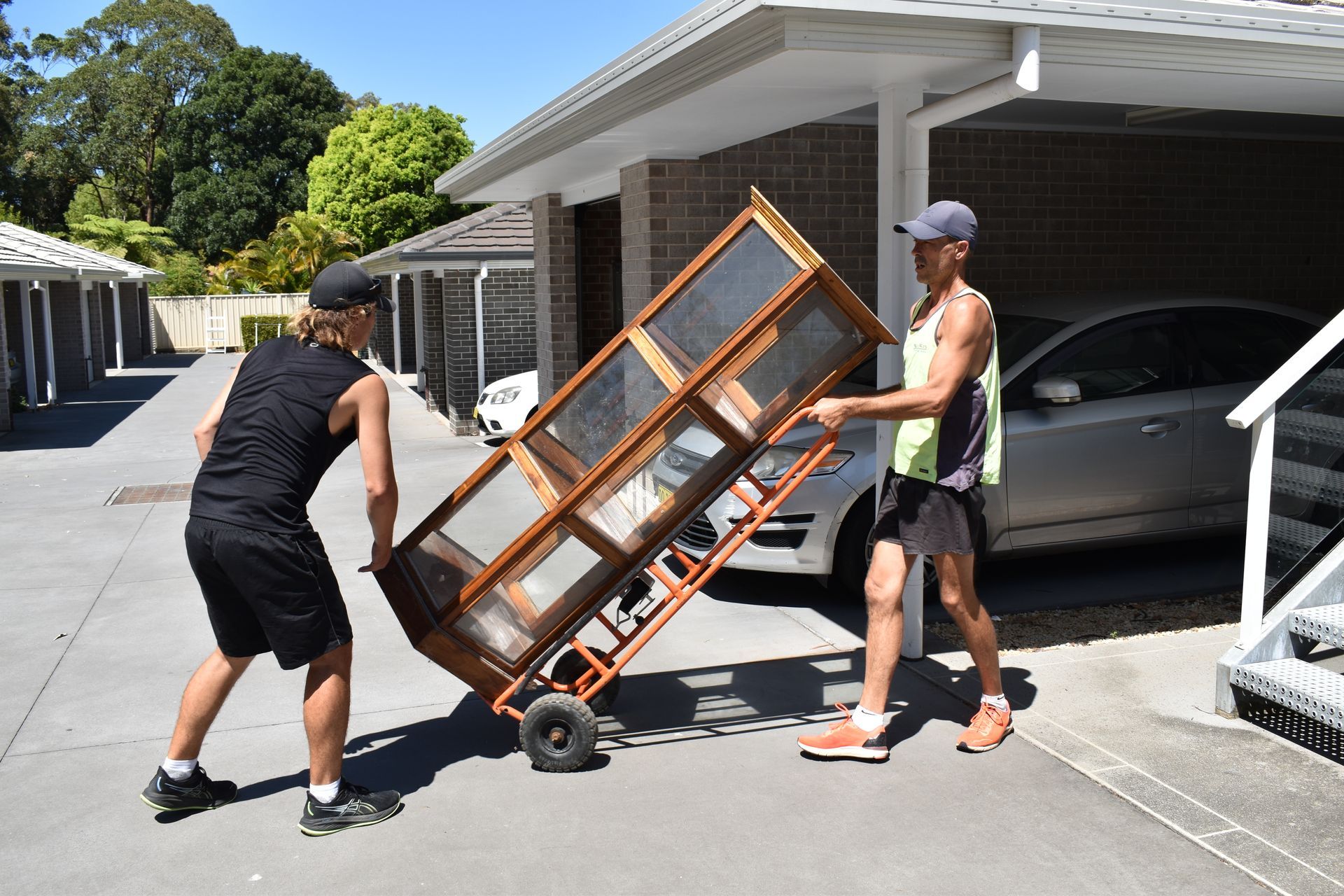 A Woman Is Holding A Cardboard Box In Front Of A Door — Frontline Removals And Storage in Newcastle, NSW