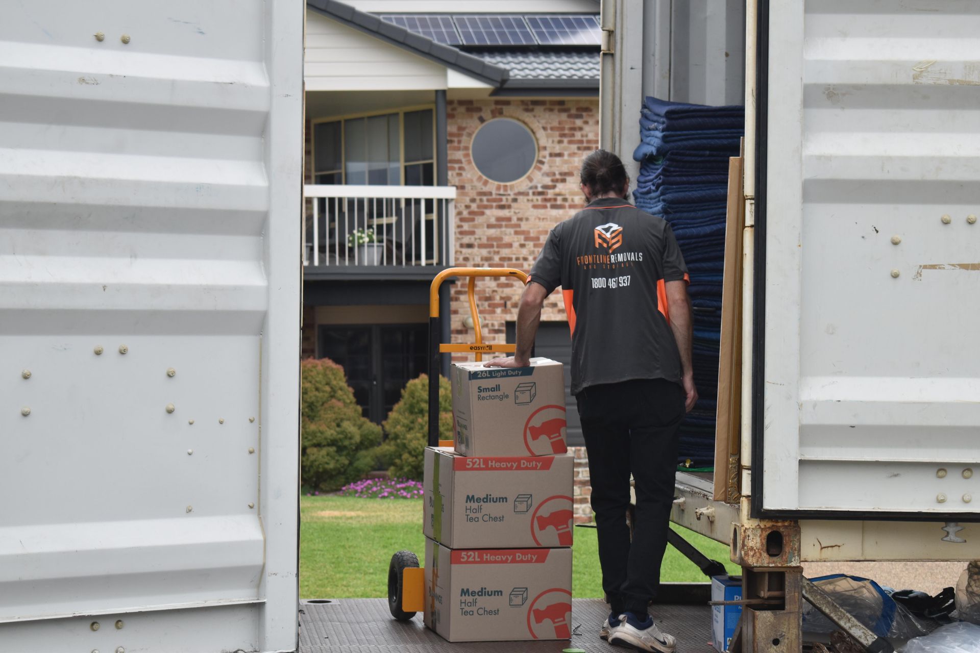 A Person Loads Boxes From a Hand Truck Into a Shipping Container; Residential Setting — Frontline Removals And Storage in Port Macquarie, NSW