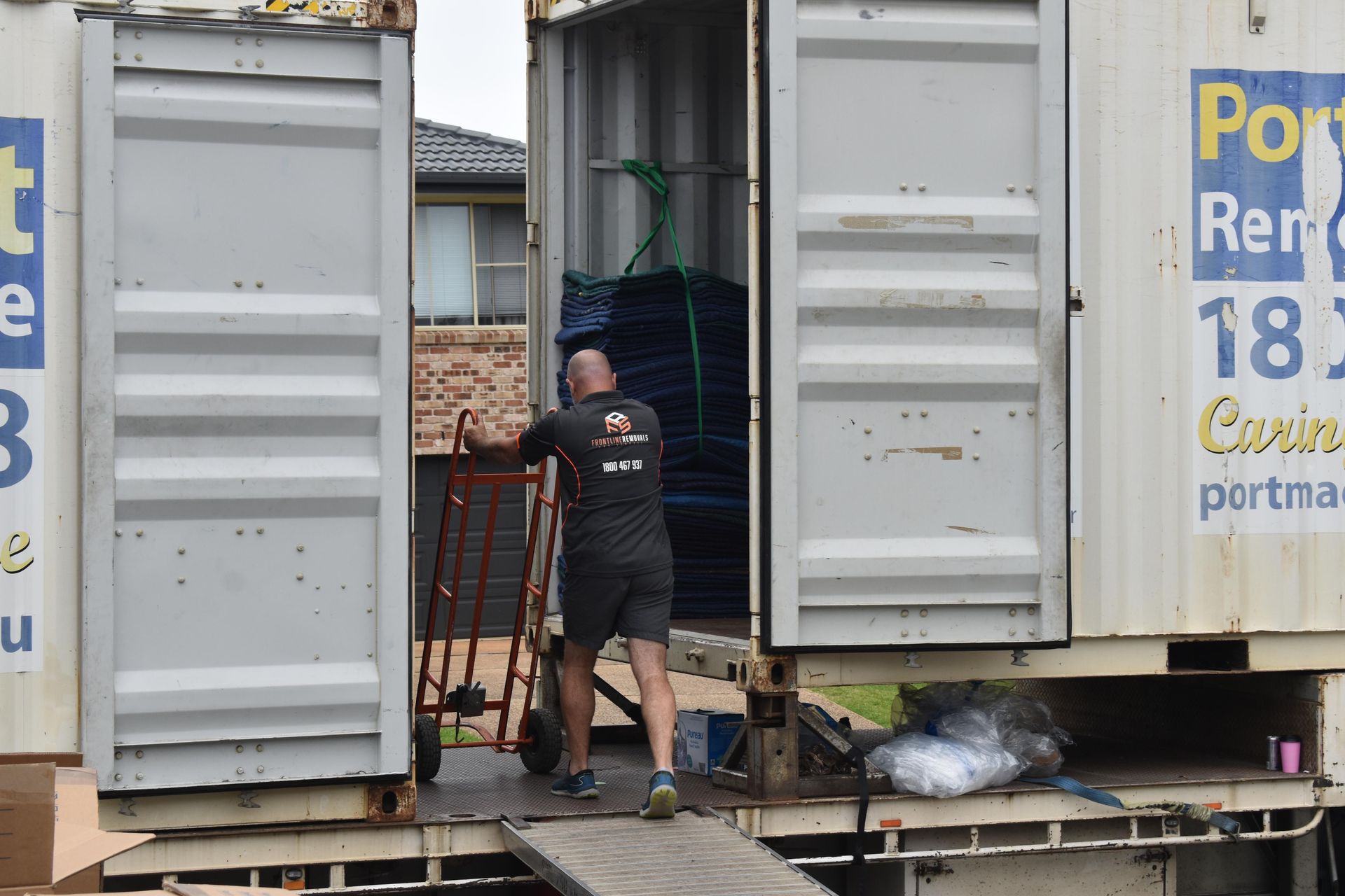 Man Loading a Storage Container With a Dolly — Frontline Removals And Storage in Port Macquarie, NSW