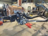 Black car chassis with engine in a garage setting.