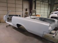 Gray car body of a convertible in a workshop, on a frame.