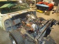 Partially disassembled vintage car in a garage, engine exposed, ready for restoration.