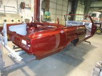 Red classic car body shell in a workshop.
