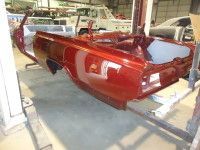 Red car chassis on a lift in a garage.