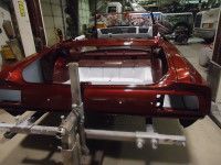 Red car body frame on a lift in a workshop.