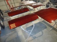 Red car body panels laid out on white sawhorses in a garage.