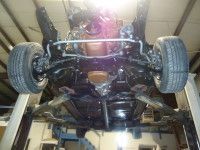 Undercarriage of a black car on a lift, showing tires, suspension, and engine components.