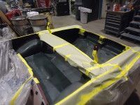 Car interior masked for painting, covered in tape and plastic sheeting.