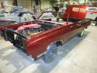 Red classic car with open hood, in a repair shop.