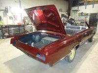 Maroon convertible car with open trunk in a garage setting.